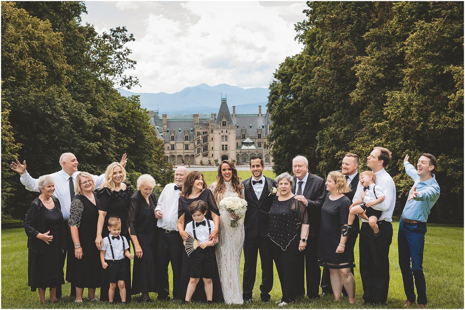 The wedding party lined up outdoors at a formal event, all dressed in black and white attire for group photos.