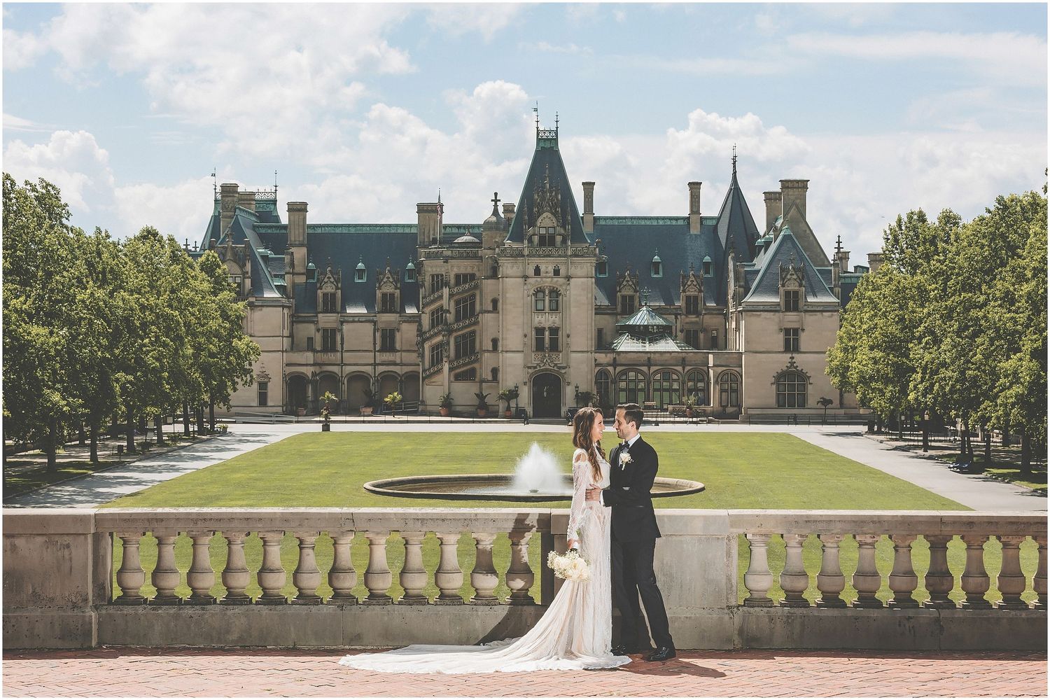 Wedding party poses for photos on the grand stone terrace of the historic Biltmore Estate on a sunny autumn day.