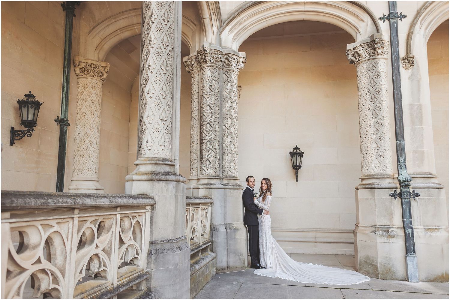 Newlyweds share romantic moments in an ornate historic colonnade with stone archways and columns at a European palace.