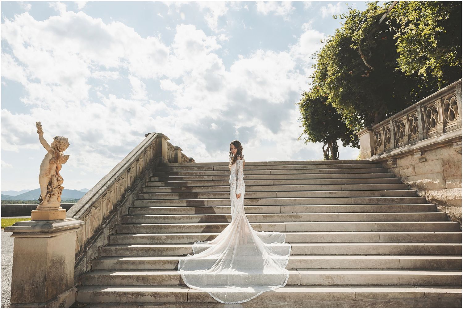 Elegant wedding photographs showcase bride in flowing white dress ascending grand stone staircase in warm sunlight.