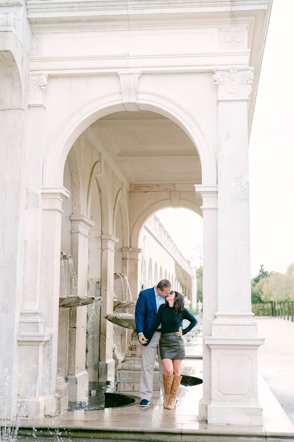 Romantic moments captured under classic white stone archways and columns.