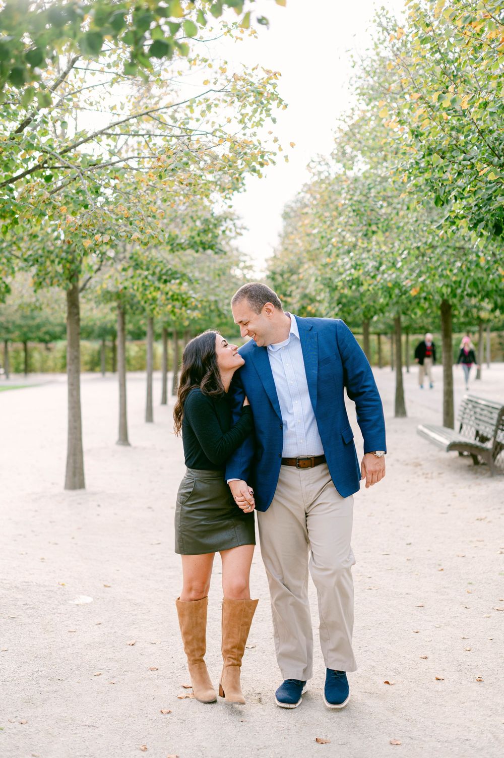 A couple shares tender moments while walking along a tree-lined path.