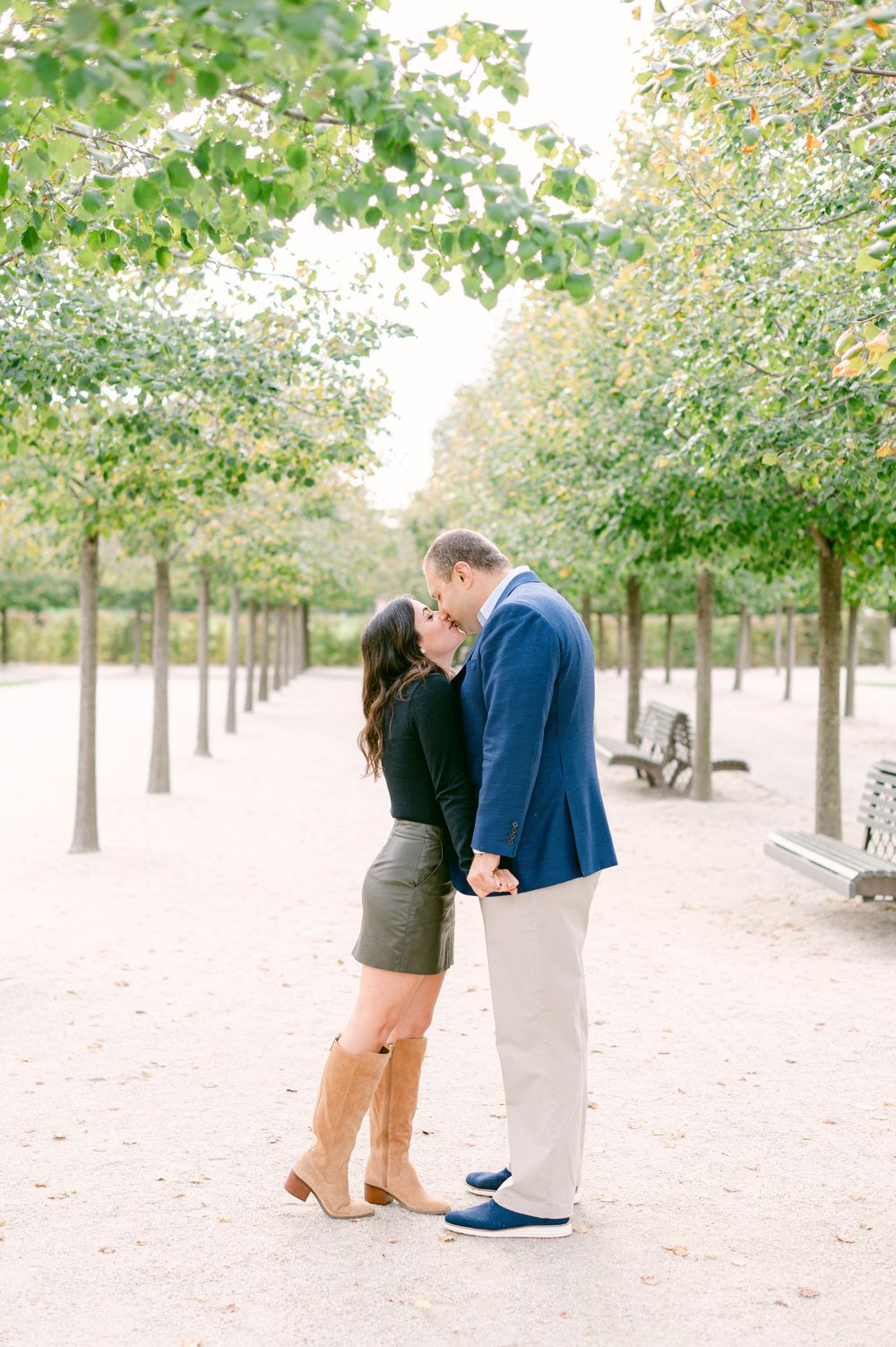 A romantic moment unfolds on a tree-lined path during an autumn photo session.