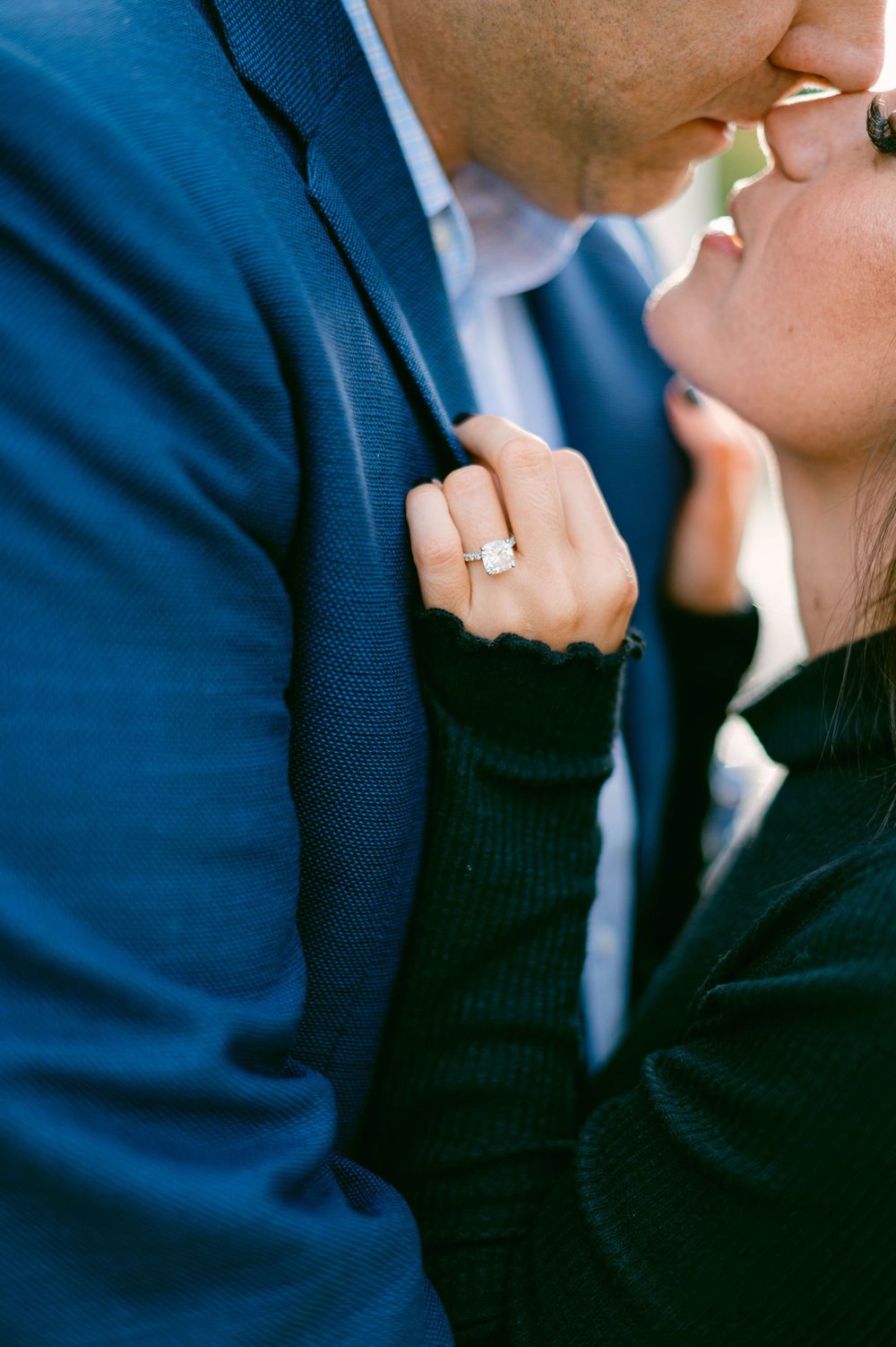 Close-up shot showcasing engagement ring while couple shares intimate moment.