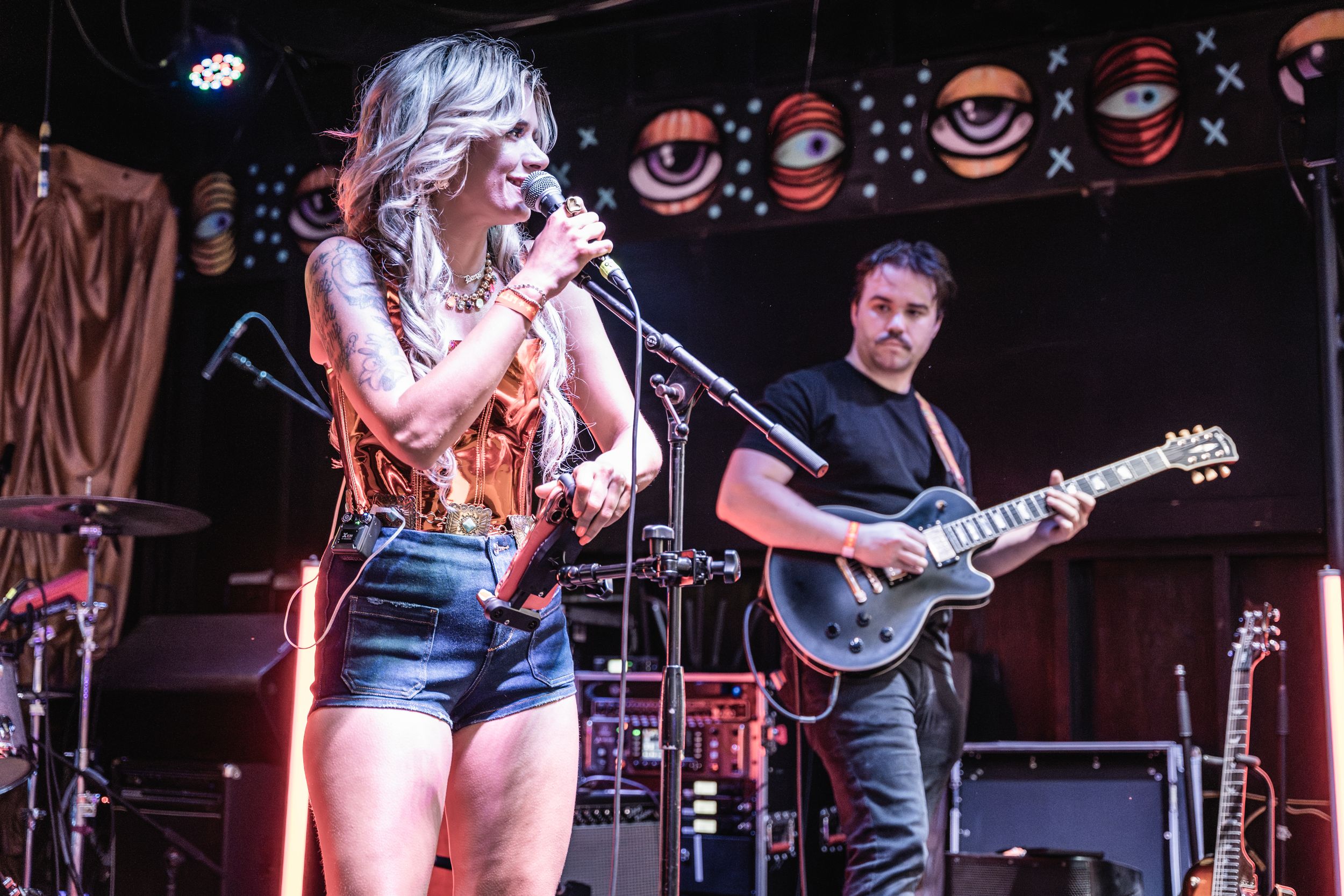 Musicians performing on stage at a live concert venue with electric guitars and instruments.
