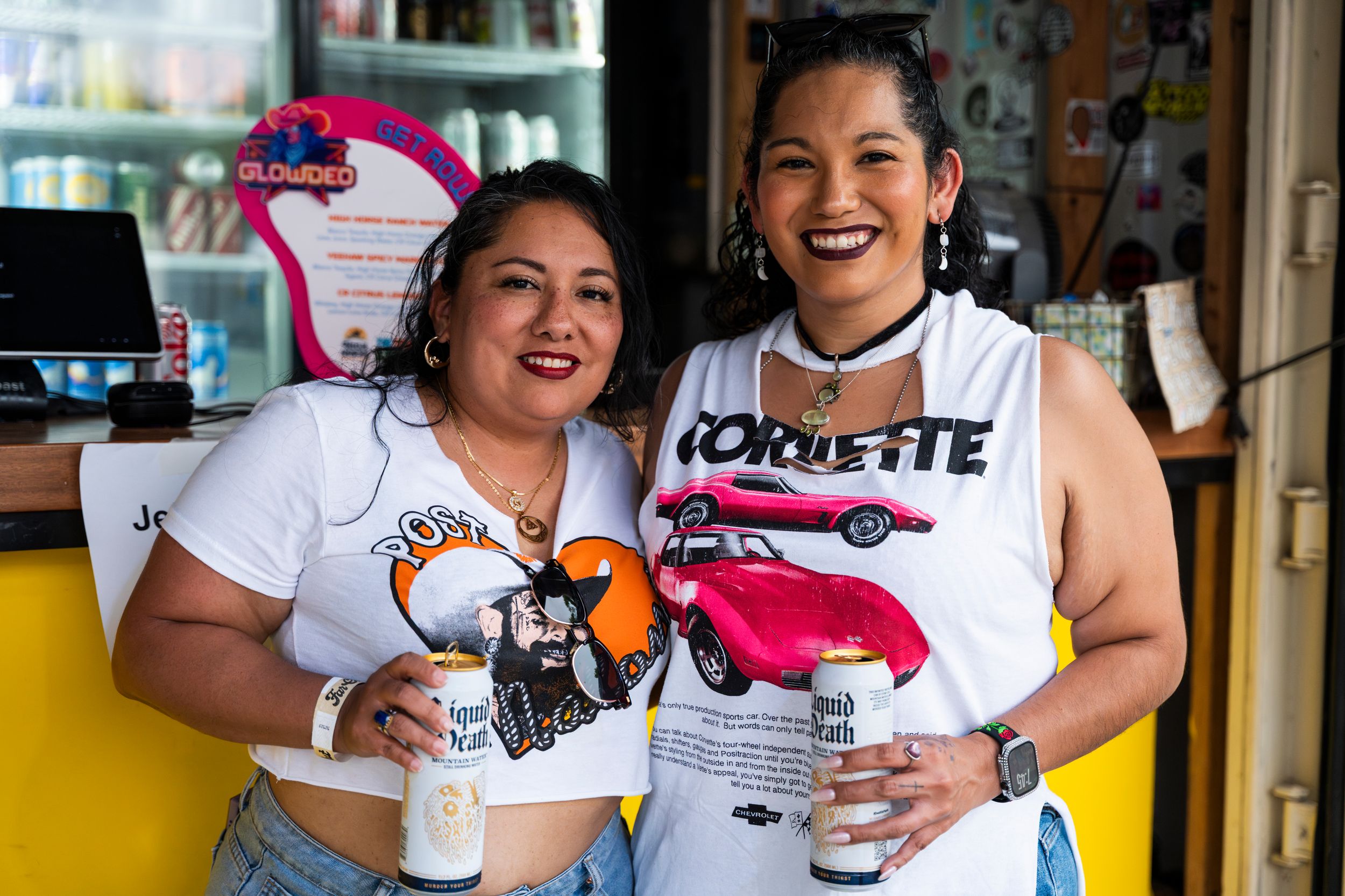 Two smiling restaurant staff members wearing graphic t-shirts pose together at a casual dining establishment.