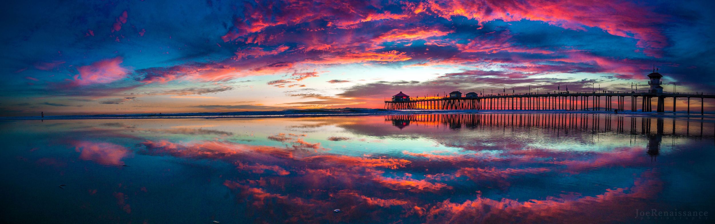 Dramatic sunset sky with vibrant pink and purple clouds reflecting over a coastal pier.