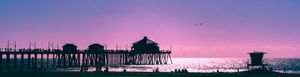 Silhouette of Huntington Beach Pier against a pastel pink sky during sunset.