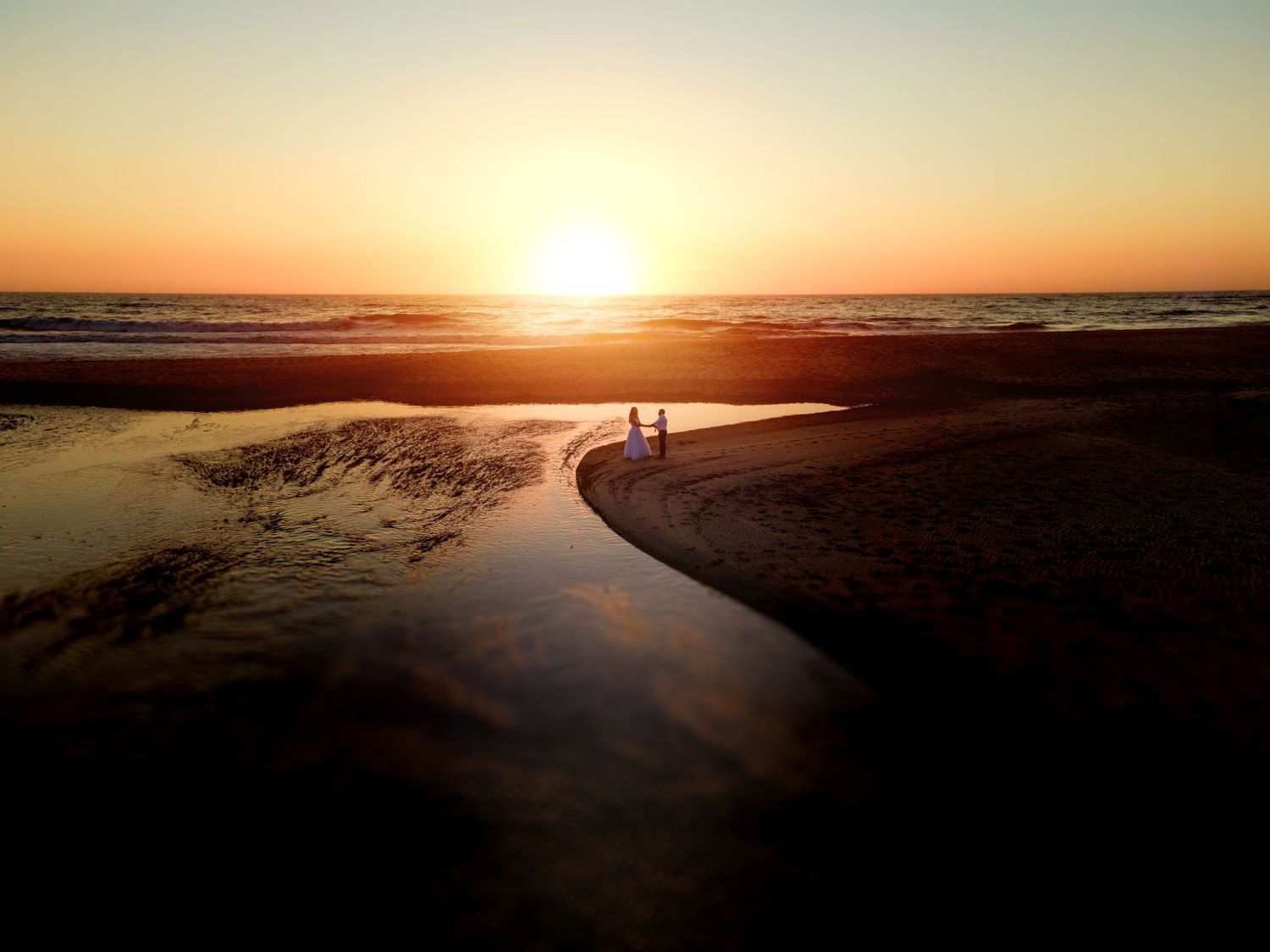Noivos no pôr do Sol na praia.