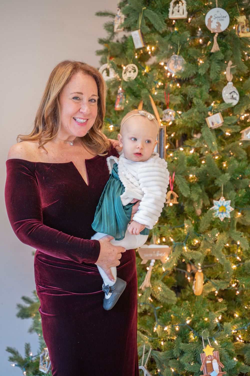 A holiday portrait in front of a decorated Christmas tree with lights and ornaments.
