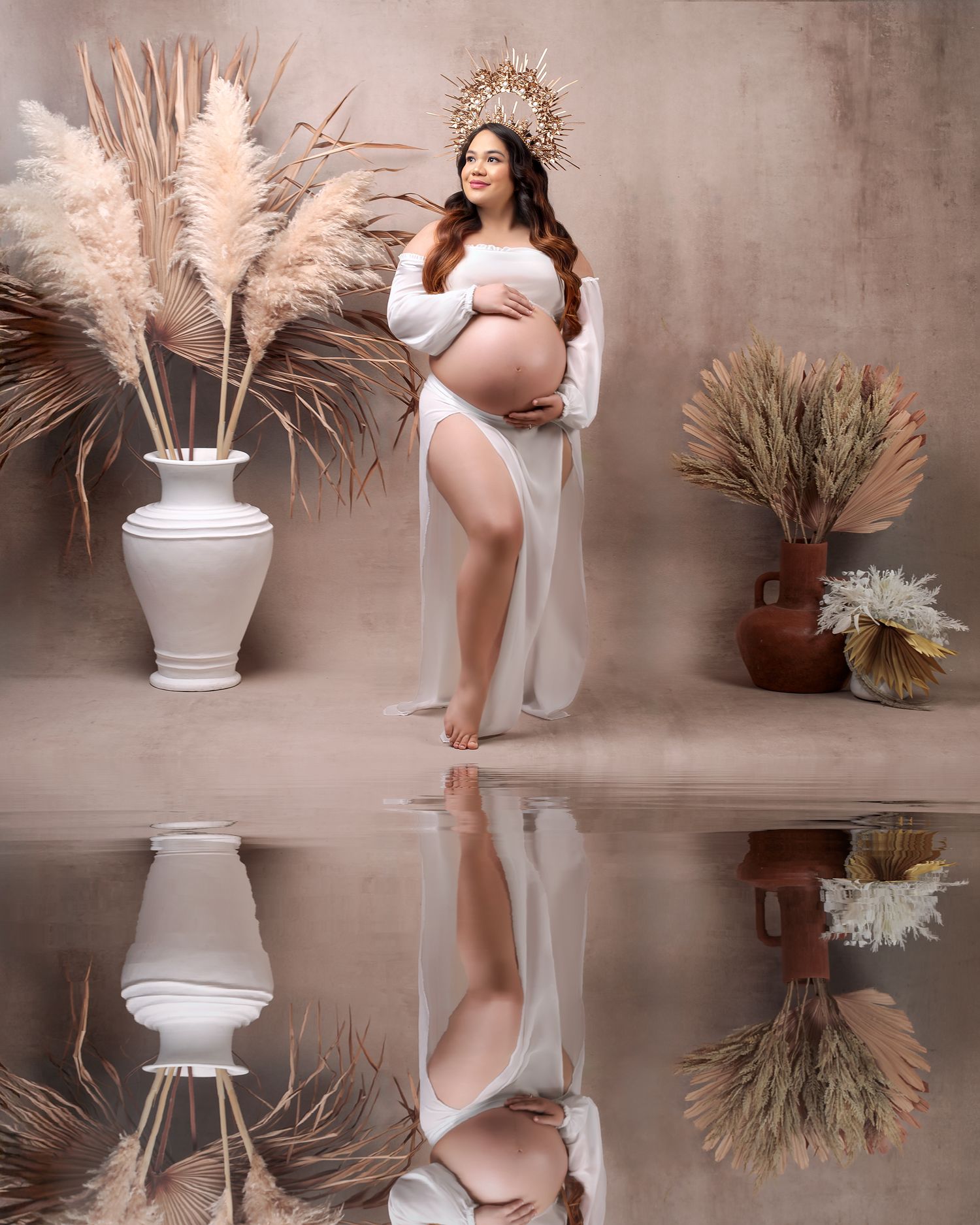 High fashion maternity: mum in a matching white sheer skirt and crop blouse, framed with dried palms, studio shot.