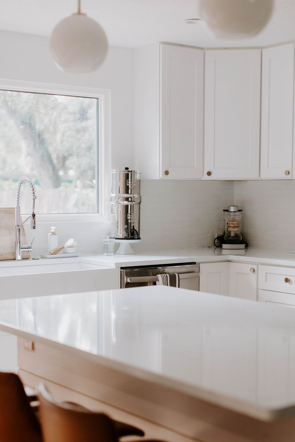 Modern white kitchen with clean countertops and natural lighting.