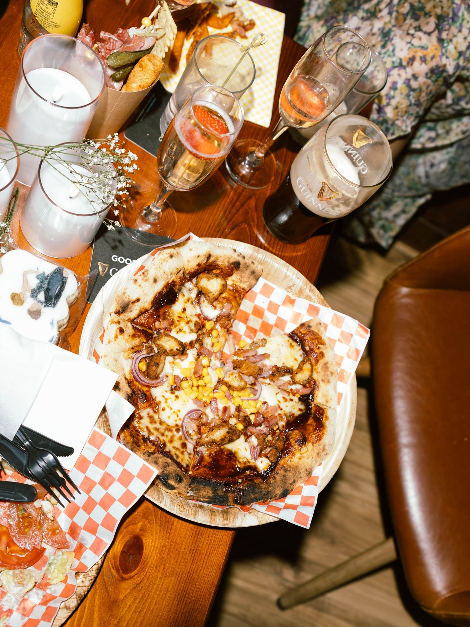 Overhead view of partially eaten pizzas and beer glasses on a wooden restaurant table.