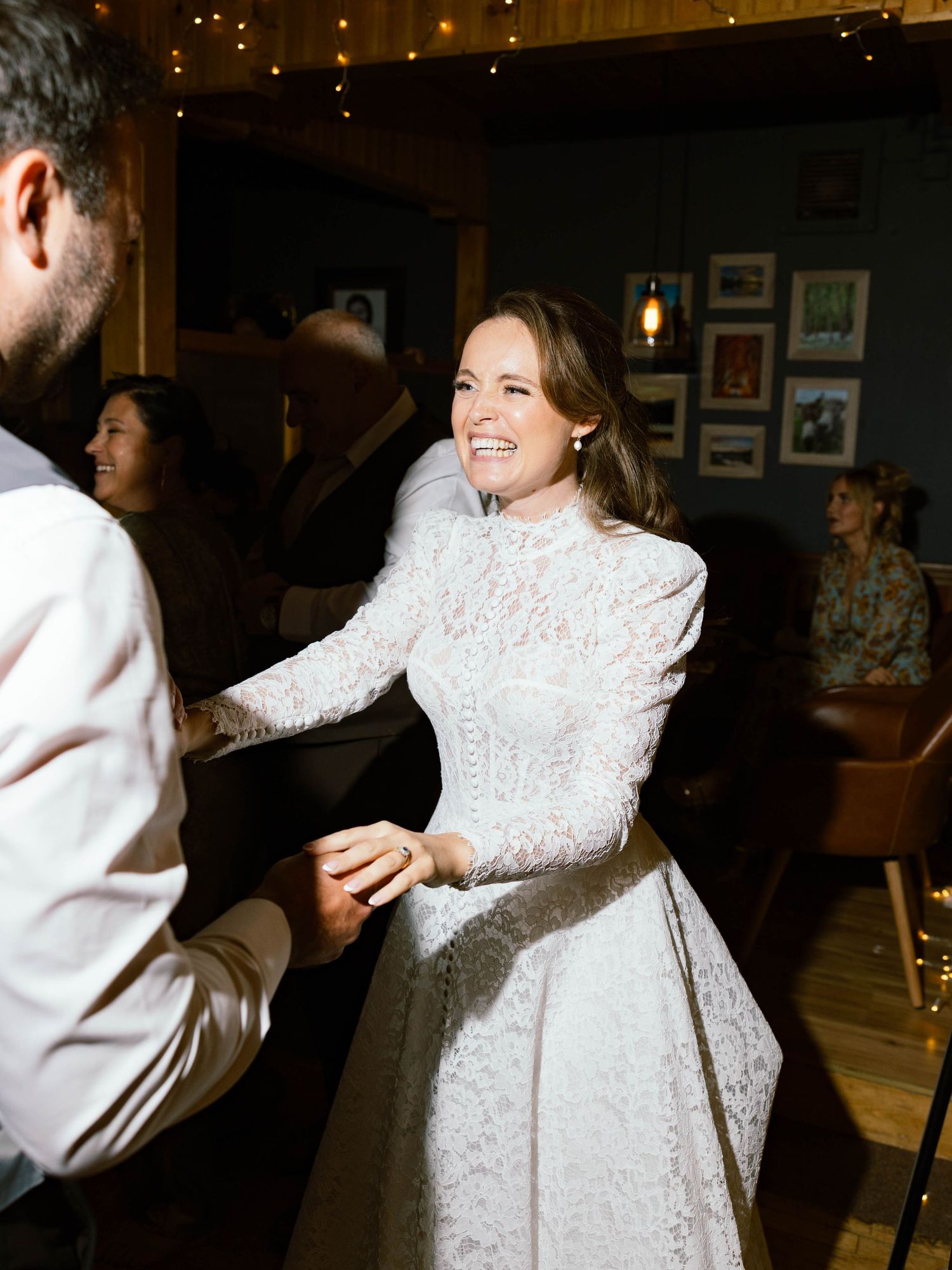 A joyful celebration moment with dancing and movement captured in a warm, intimate indoor setting.