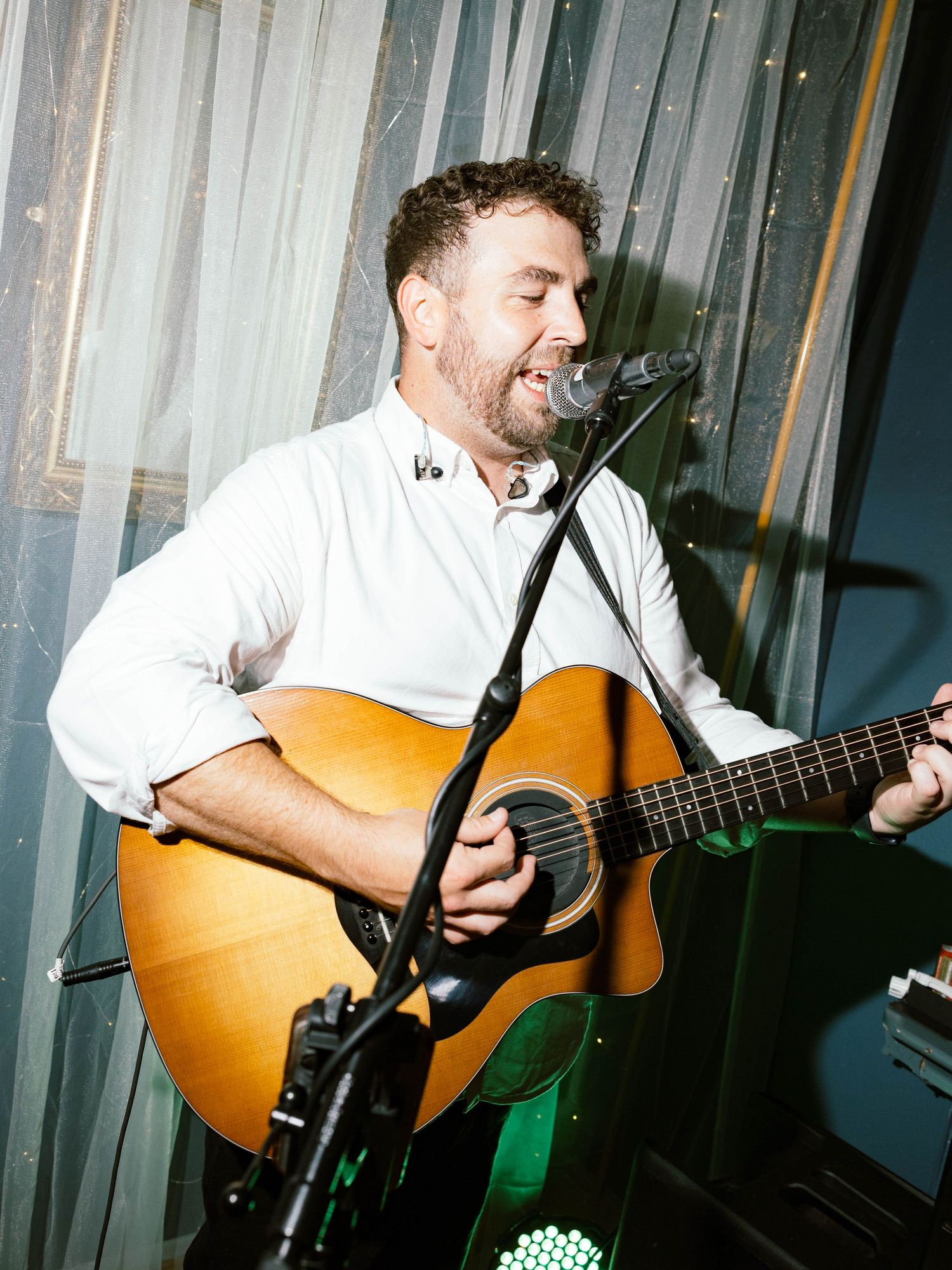 Someone plays an acoustic guitar in a dimly lit space with blurred overlapping exposure creating an artistic effect.