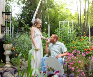 A couple enjoys a romantic moment in a garden filled with colorful flowers and greenery.