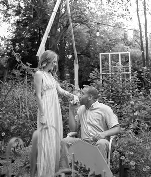 Black and white portrait of a couple sharing intimate moments in a garden setting.