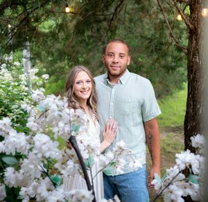 A couple shares tender moments near white cherry blossoms in a garden setting.
