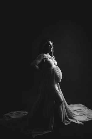 A graceful dancer in a white dress creates dramatic silhouettes against a dark background in this artistic photo series.