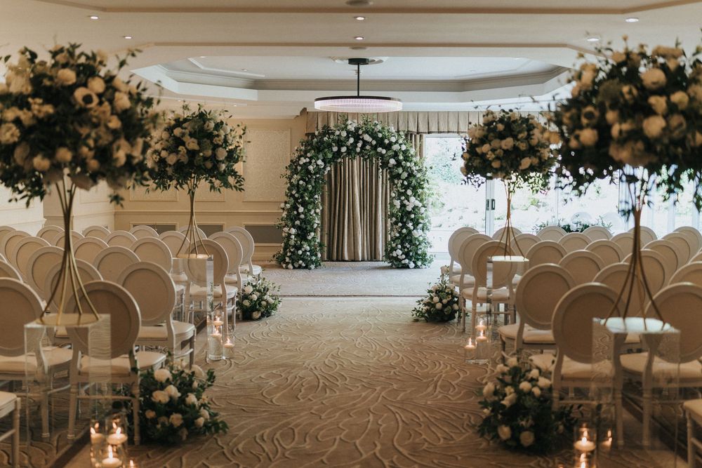 A luxuriously decorated indoor wedding venue featuring elegant white floral arrangements and soft ambient lighting.