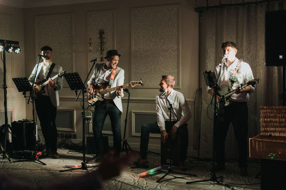 Musicians performing in a recording studio, with instruments and microphones set up in a dimly lit environment.