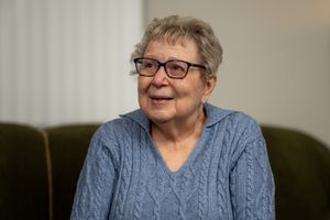 A cozy portrait of someone wearing glasses and a blue cable knit sweater while sitting on a green couch.