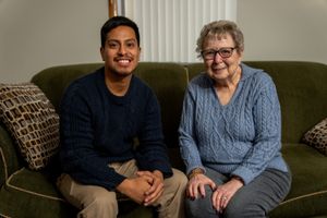 Two people sit together on a green couch in a living room, sharing a warm moment.