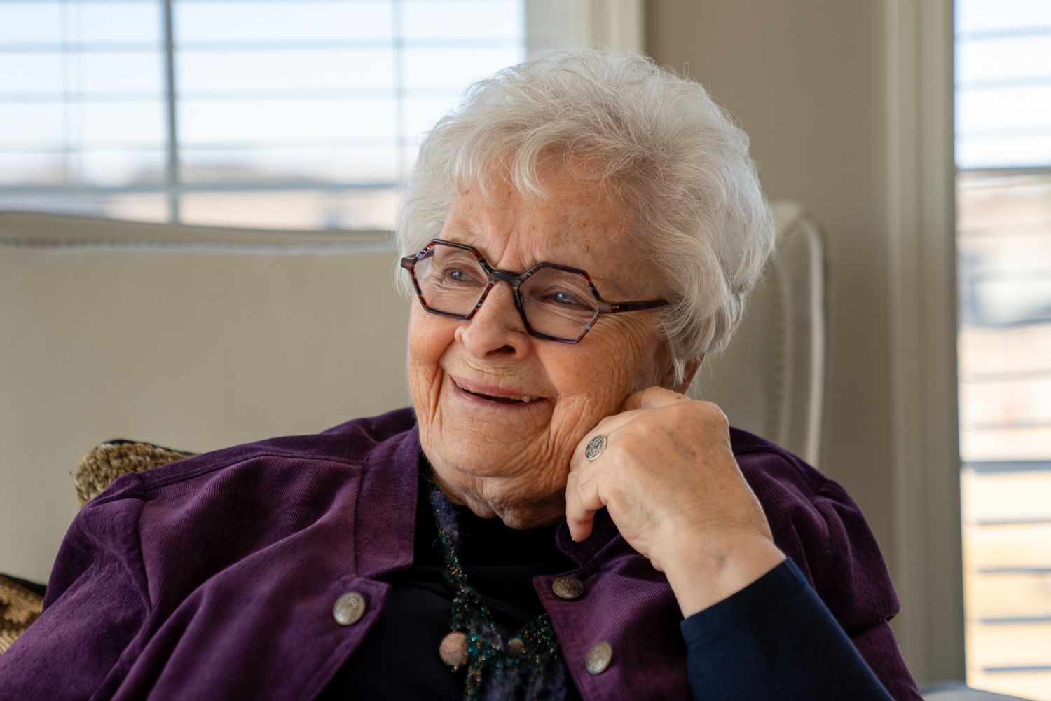 Profile views of person wearing purple top sitting by window with natural light.