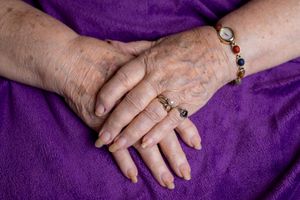 Close up detail shots of hands with jewelry resting on purple fabric.