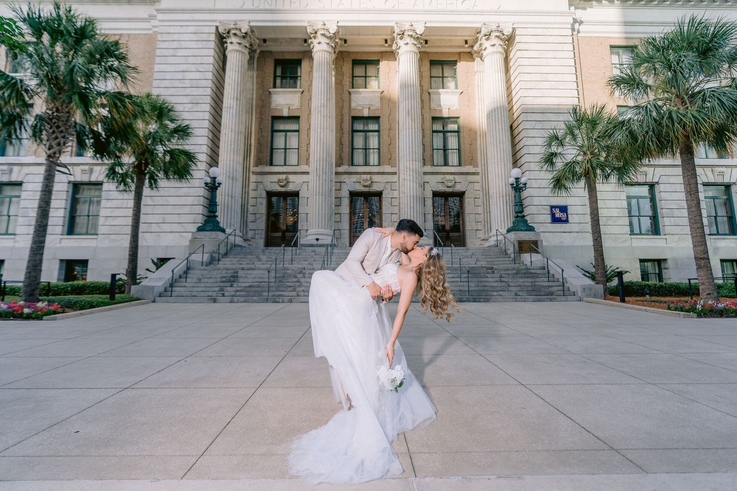 A romantic moment captured at Le Meridien, Tampa, steps with palm trees and classical columns in the background.