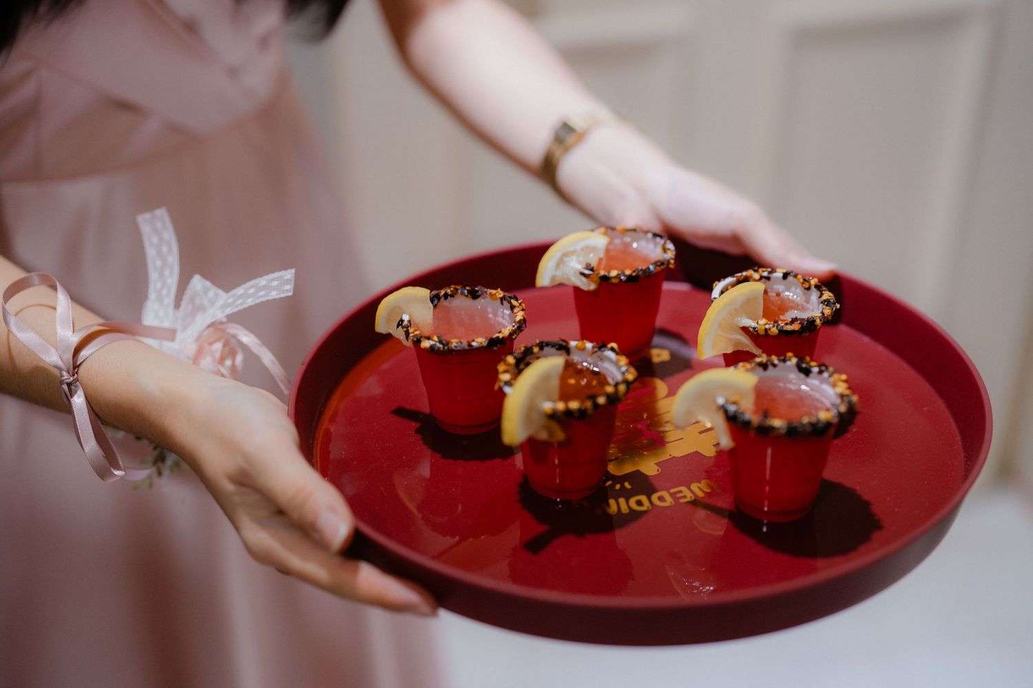Red serving platter with traditional wedding favors being presented to guests.