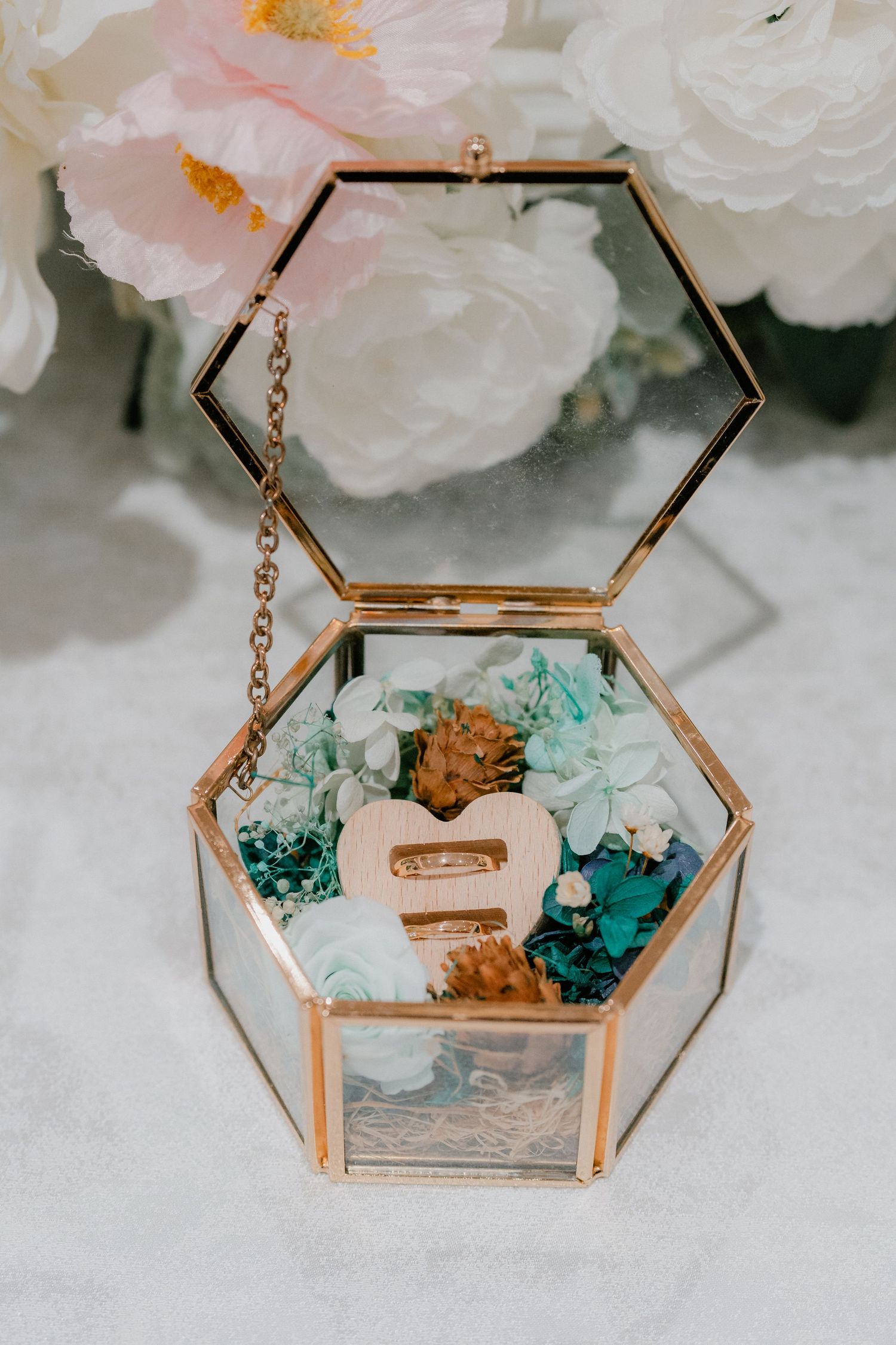 Rose gold hexagonal glass display box with delicate turquoise decorative elements inside.