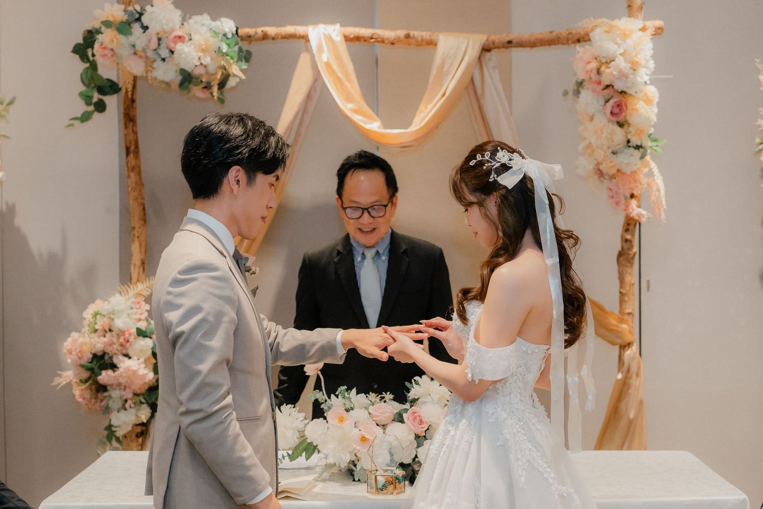 Wedding ceremony setup with wooden arch decorated in peach and white flowers.