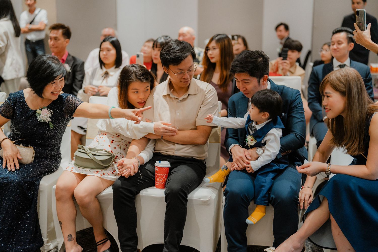 Wedding guests seated in casual attire watching a presentation or performance.