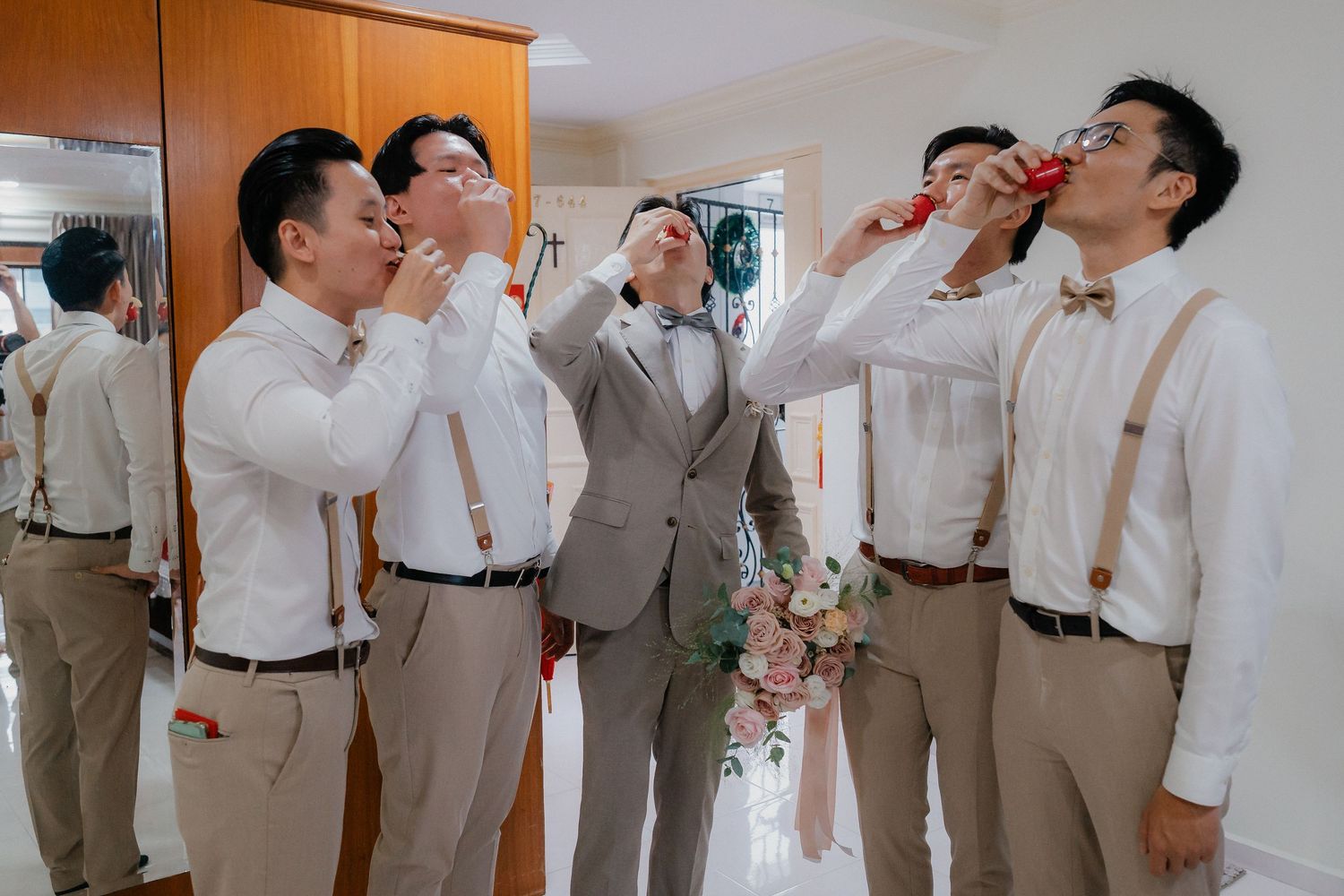 Groomsmen in matching beige suits gather for celebratory drinks.