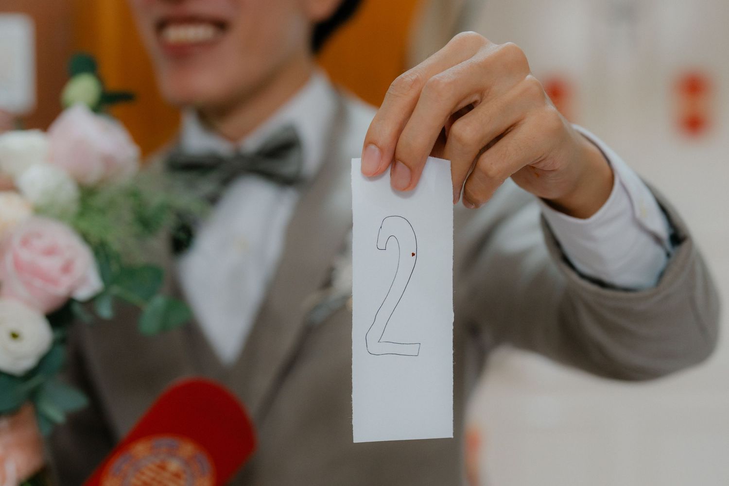 Close-up of hand holding number two card during wedding festivities.