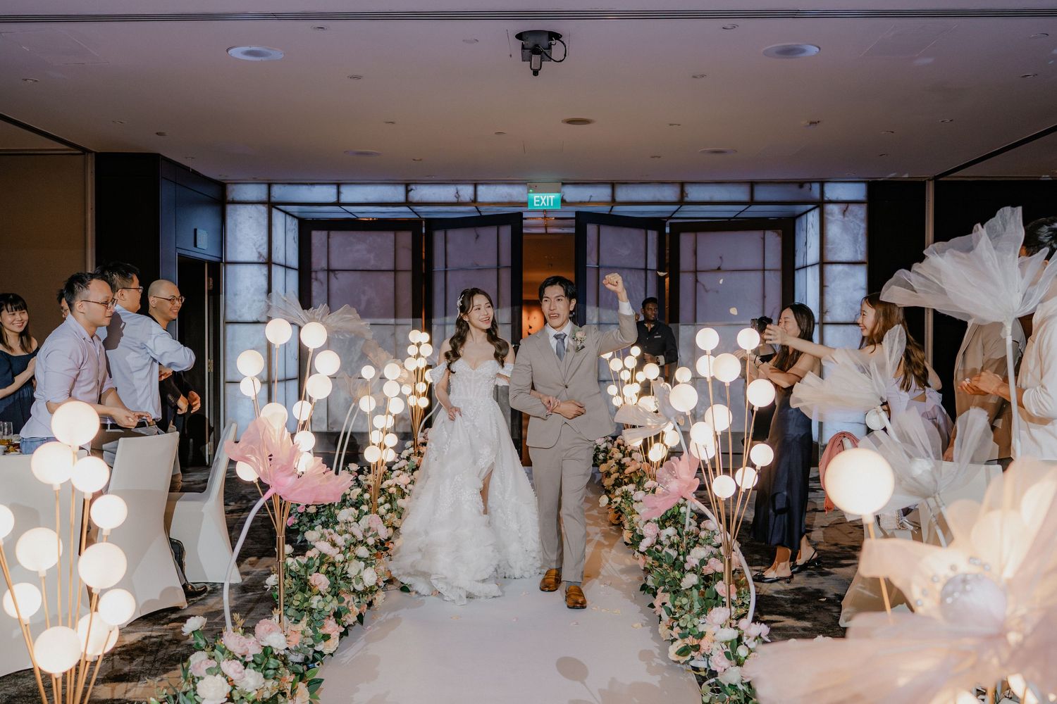 Elegant wedding ceremony space with glowing orb lights and pink floral arrangements.