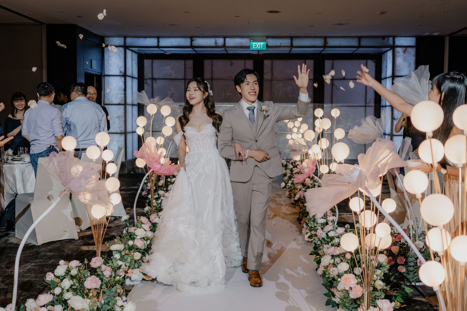 Modern wedding reception space adorned with glowing orb lights and pink floral installations.