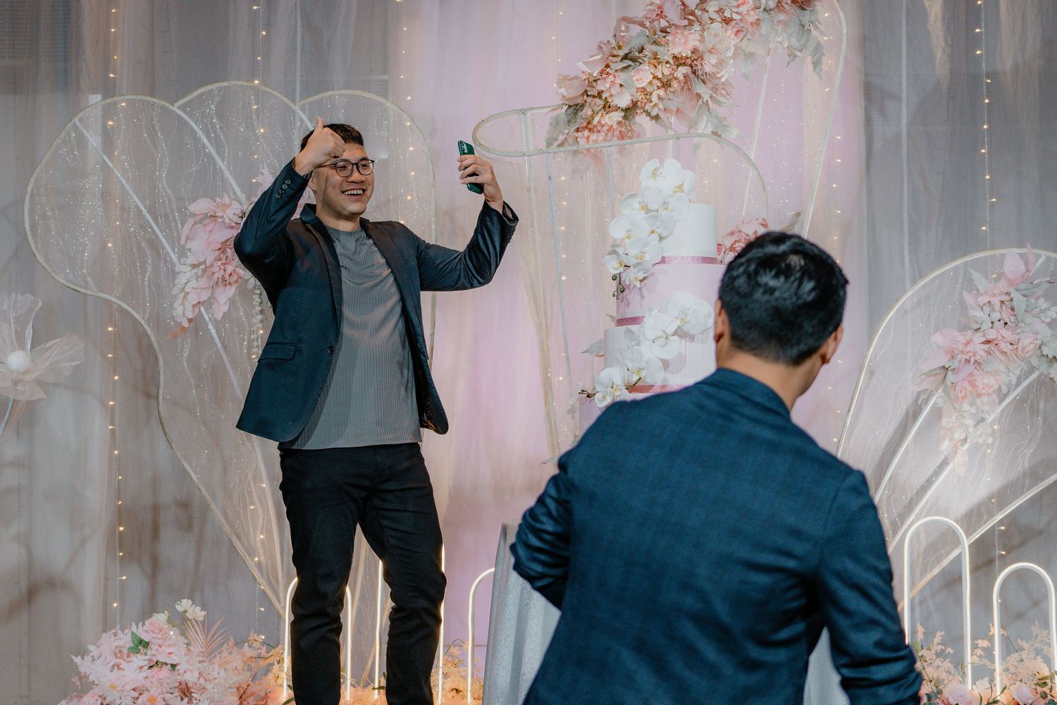 Wedding celebration with fairy lights and floral arch decorations in an indoor venue.