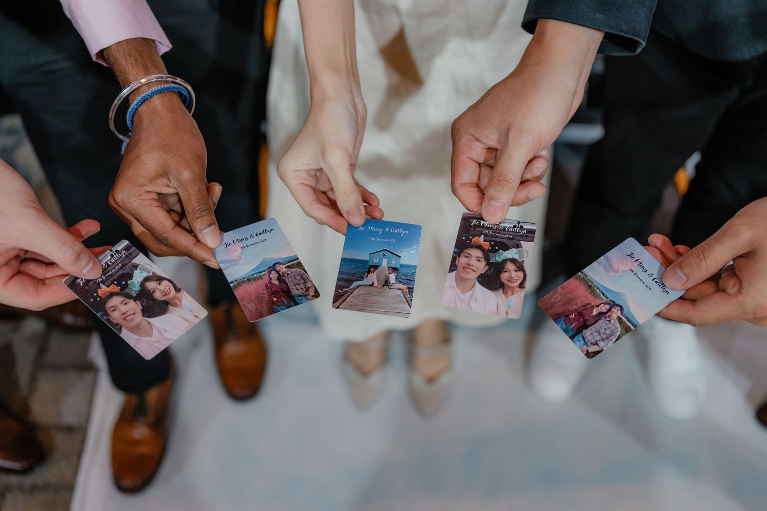 Close-up of hands holding photos during a wedding reception gathering.