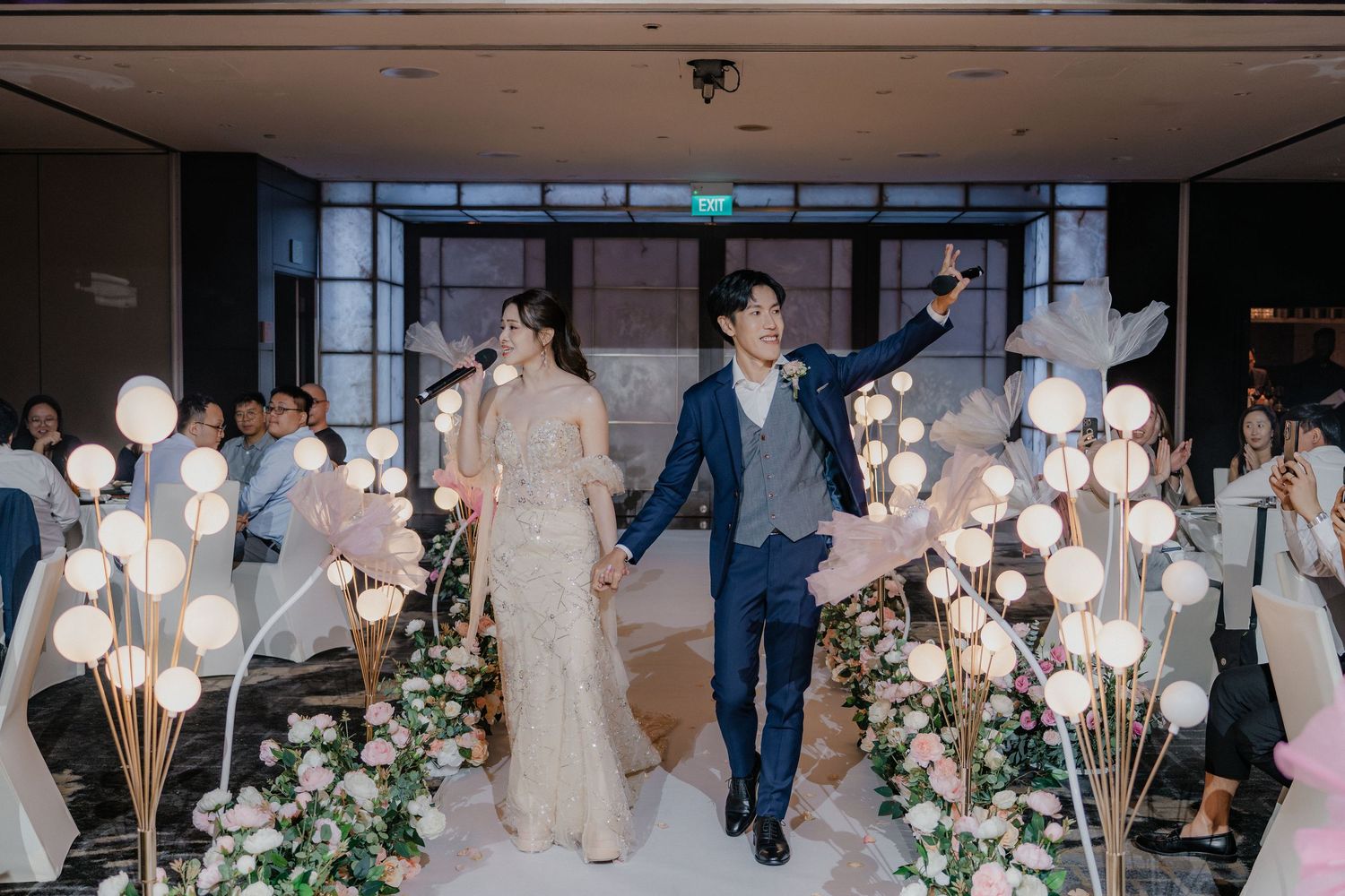 Contemporary wedding venue with glass walls, orb lighting and floral decor.