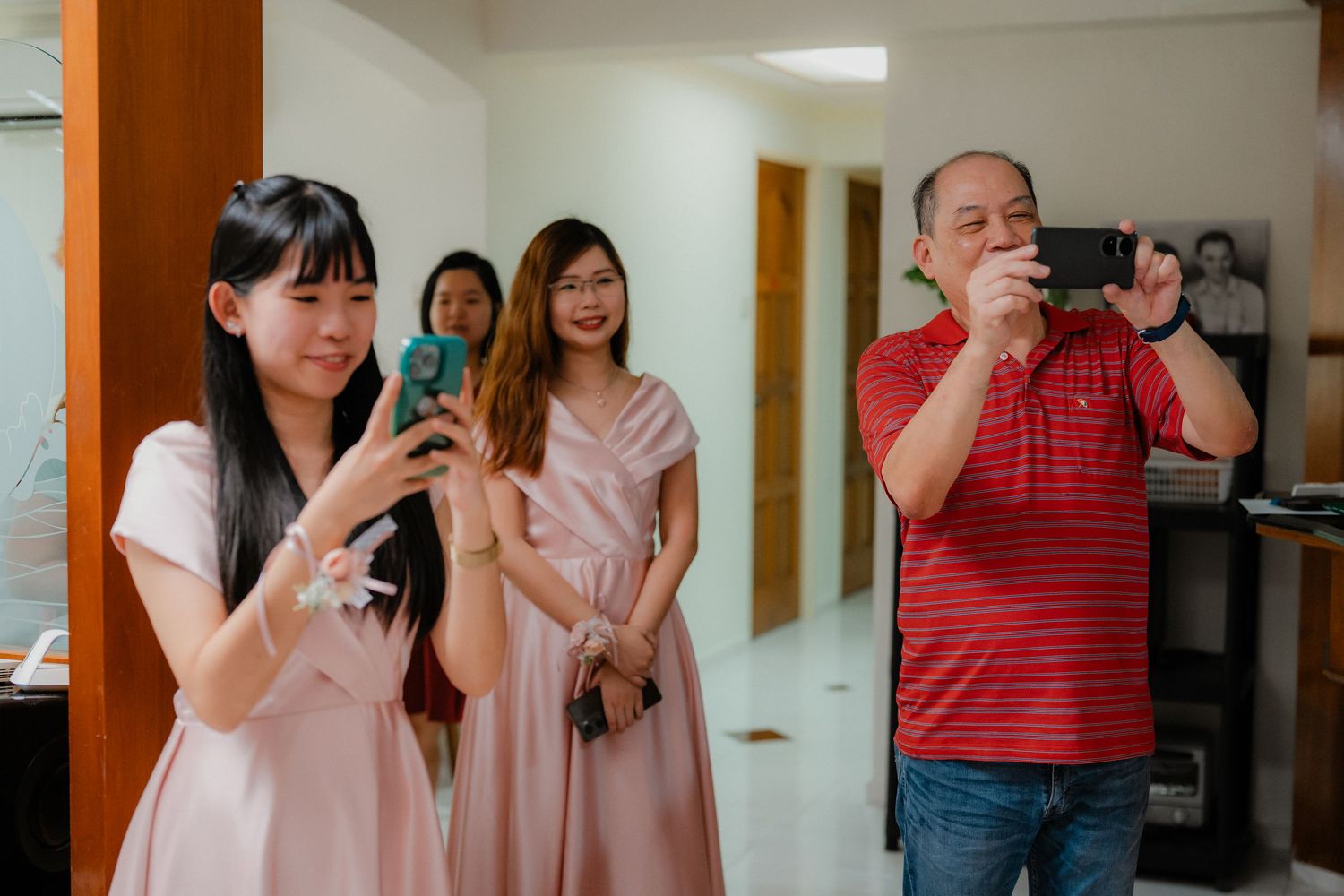 Wedding guests taking photos with smartphones in an indoor venue.