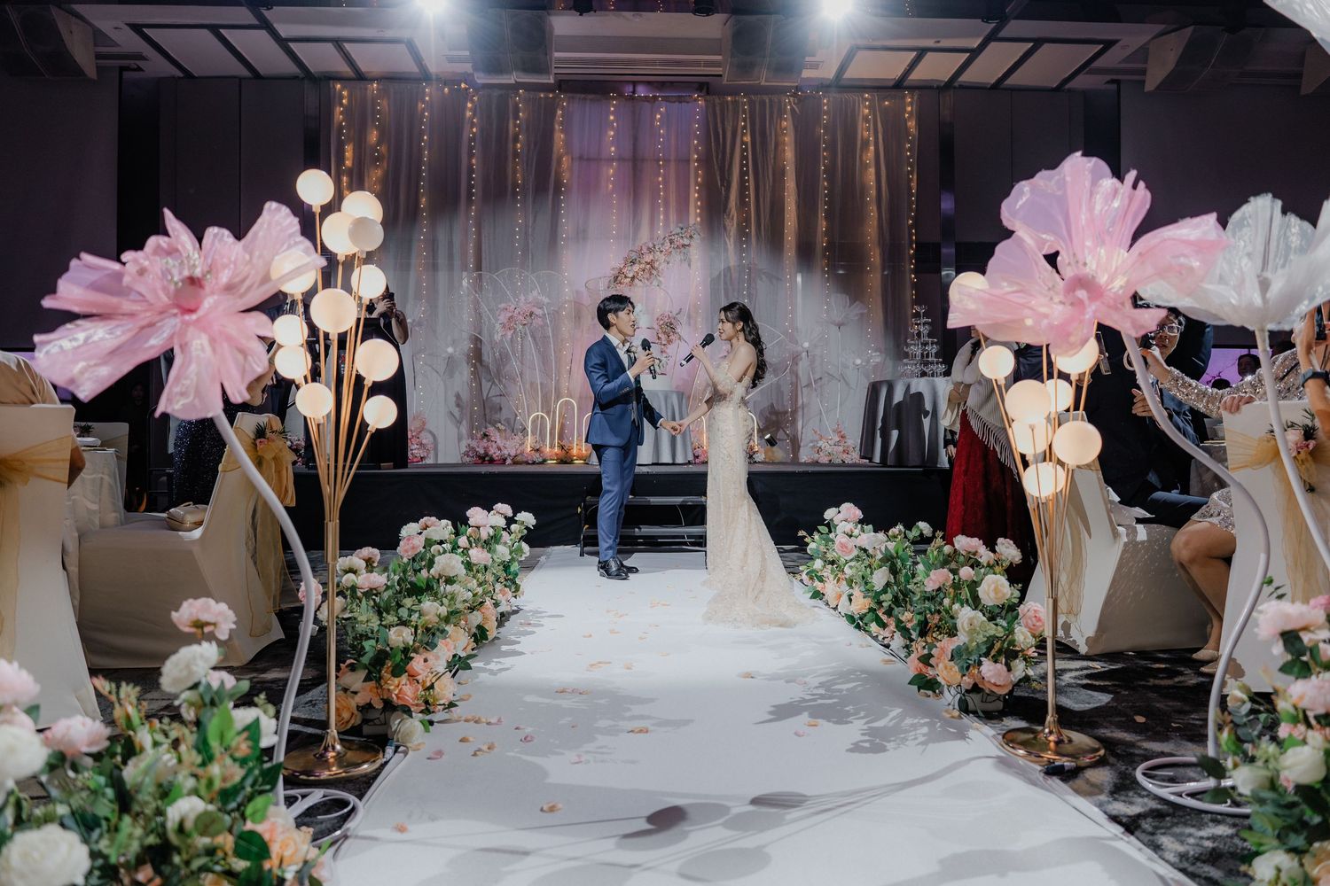 Wedding ceremony space decorated with oversized pink flowers and a white aisle runner.