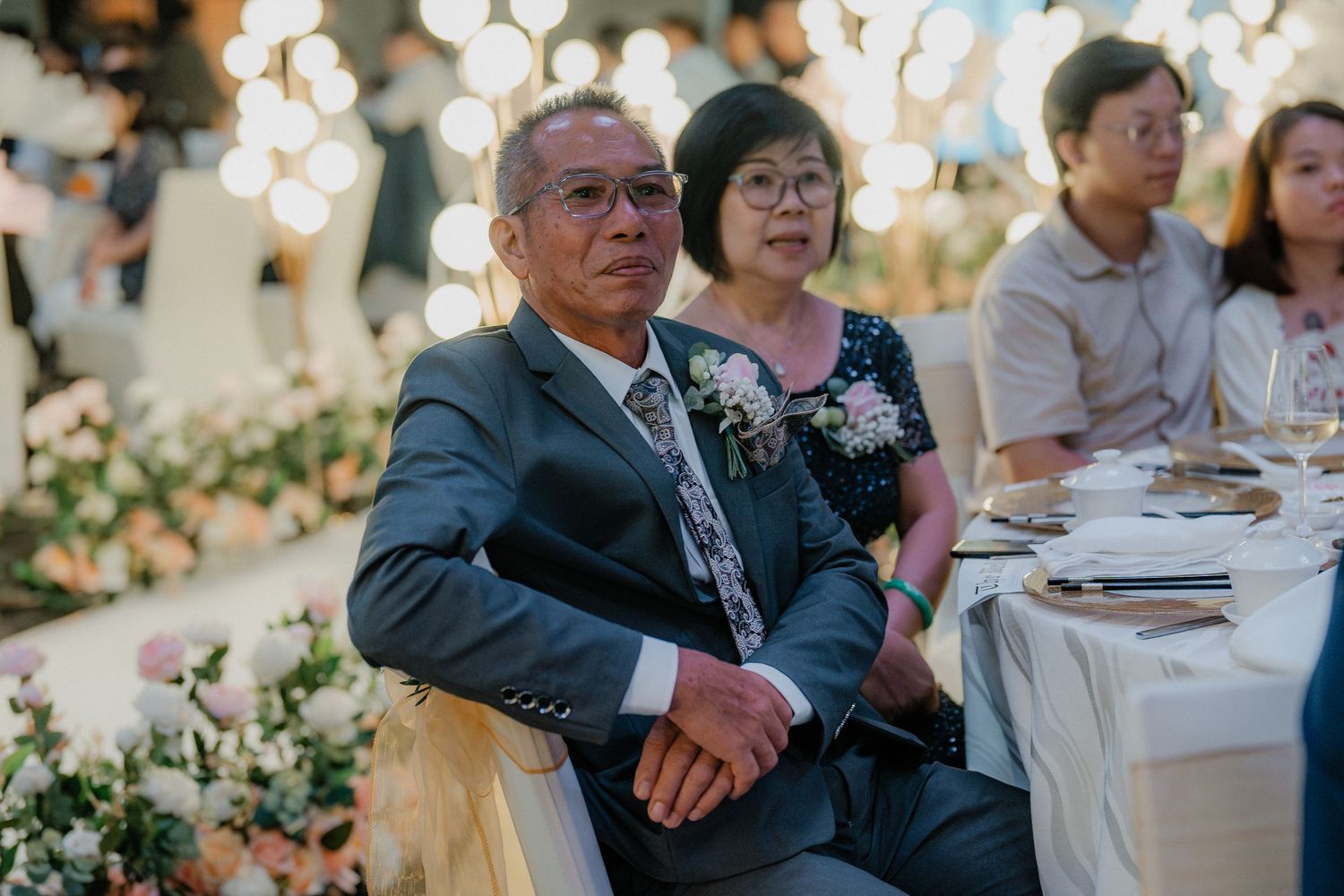 Wedding guests seated at an elegantly decorated outdoor reception table with bokeh lights.