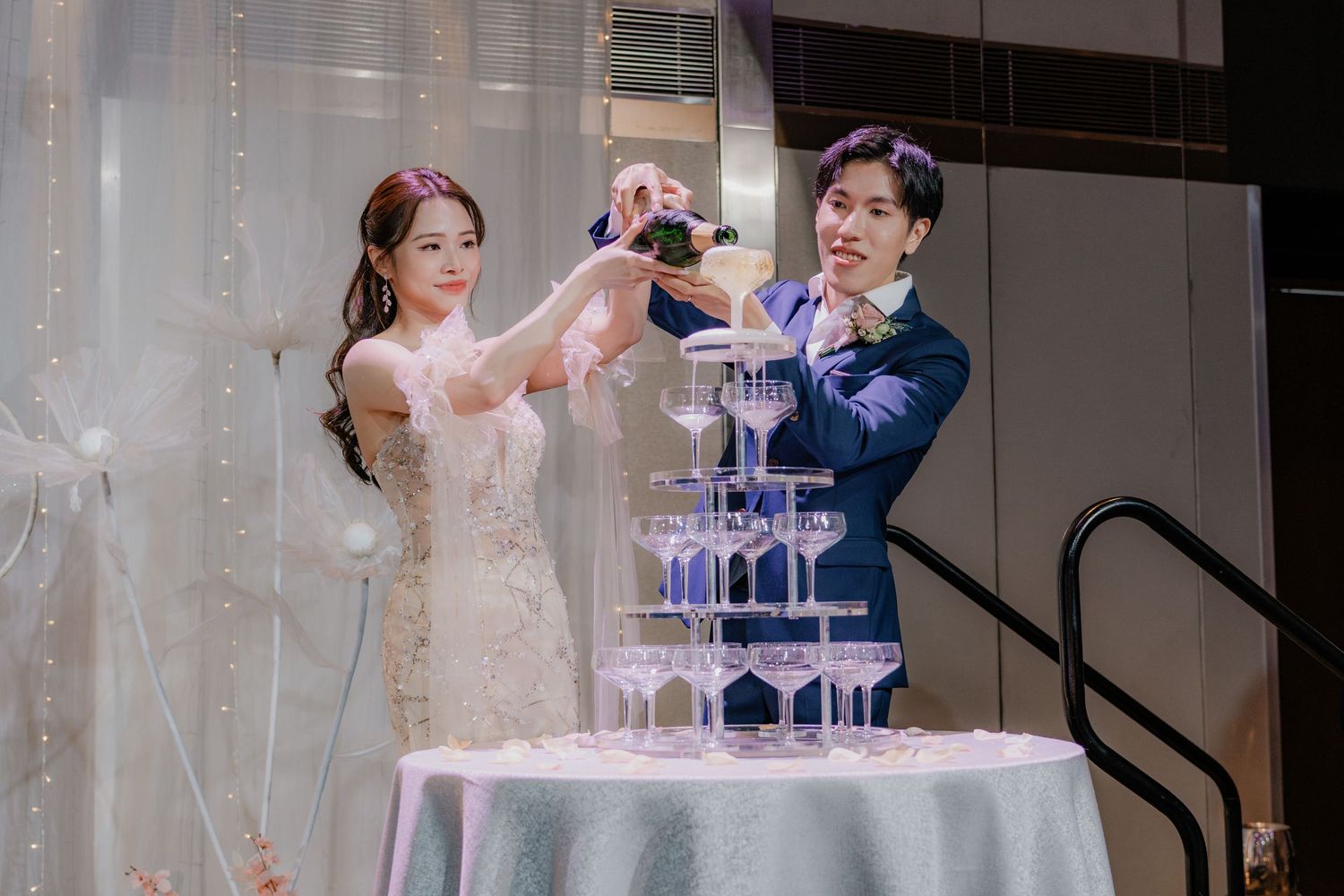 Champagne being poured into a tower of glasses during an elegant wedding reception.
