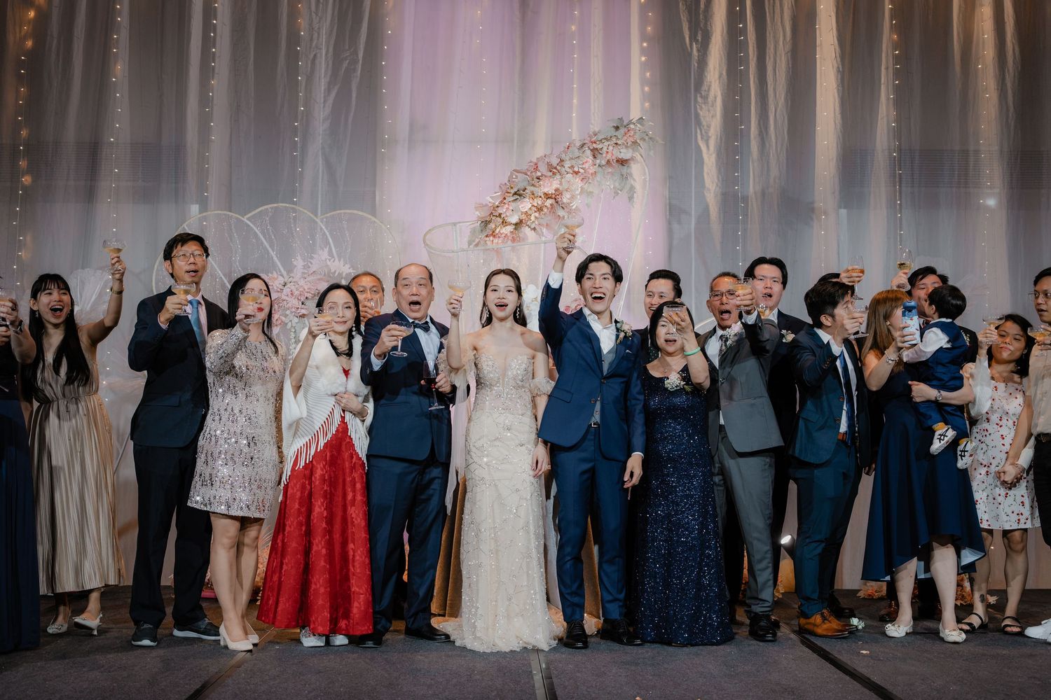 Wedding reception guests and wedding party line up against an elegant draped backdrop.