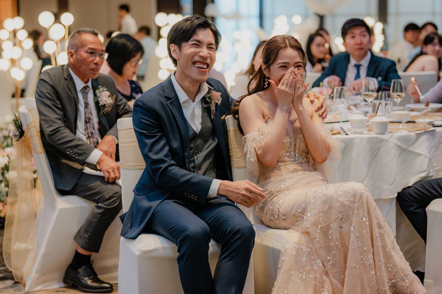 Guests and newlyweds sharing joyful reactions during wedding reception speeches.