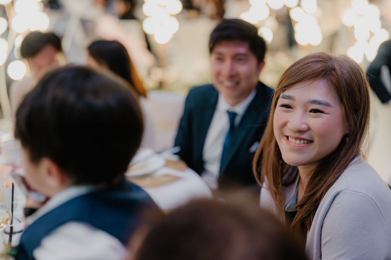 Wedding guests enjoying a reception celebration with festive bokeh lights in the background.