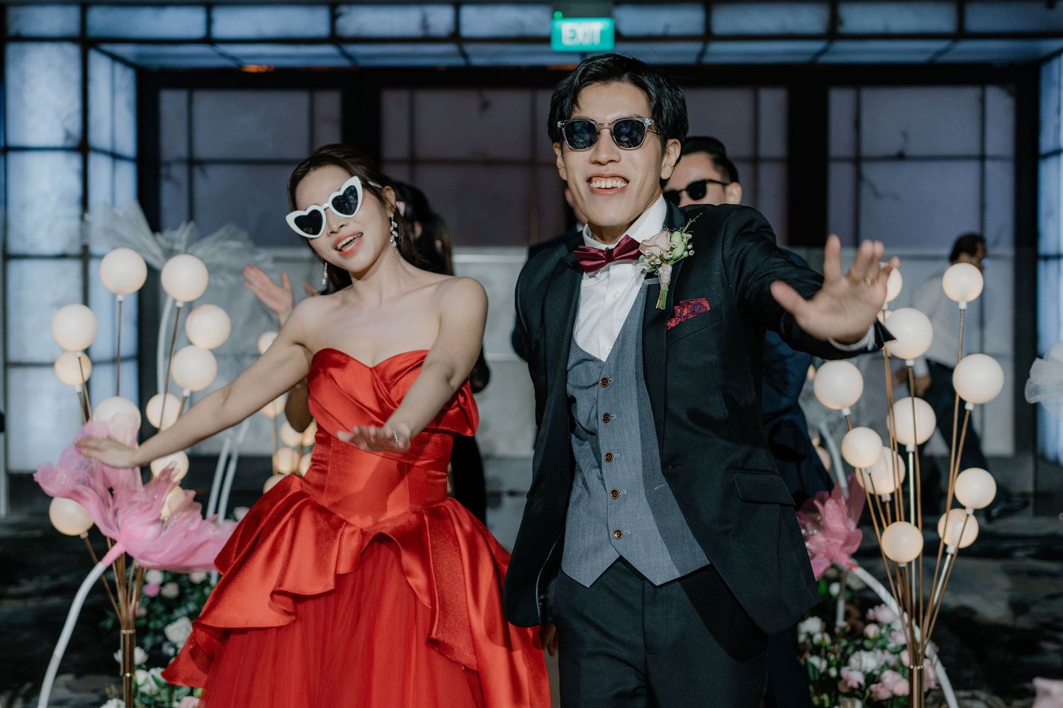 Wedding celebration with vibrant red attire and sunglasses in a contemporary indoor setting.