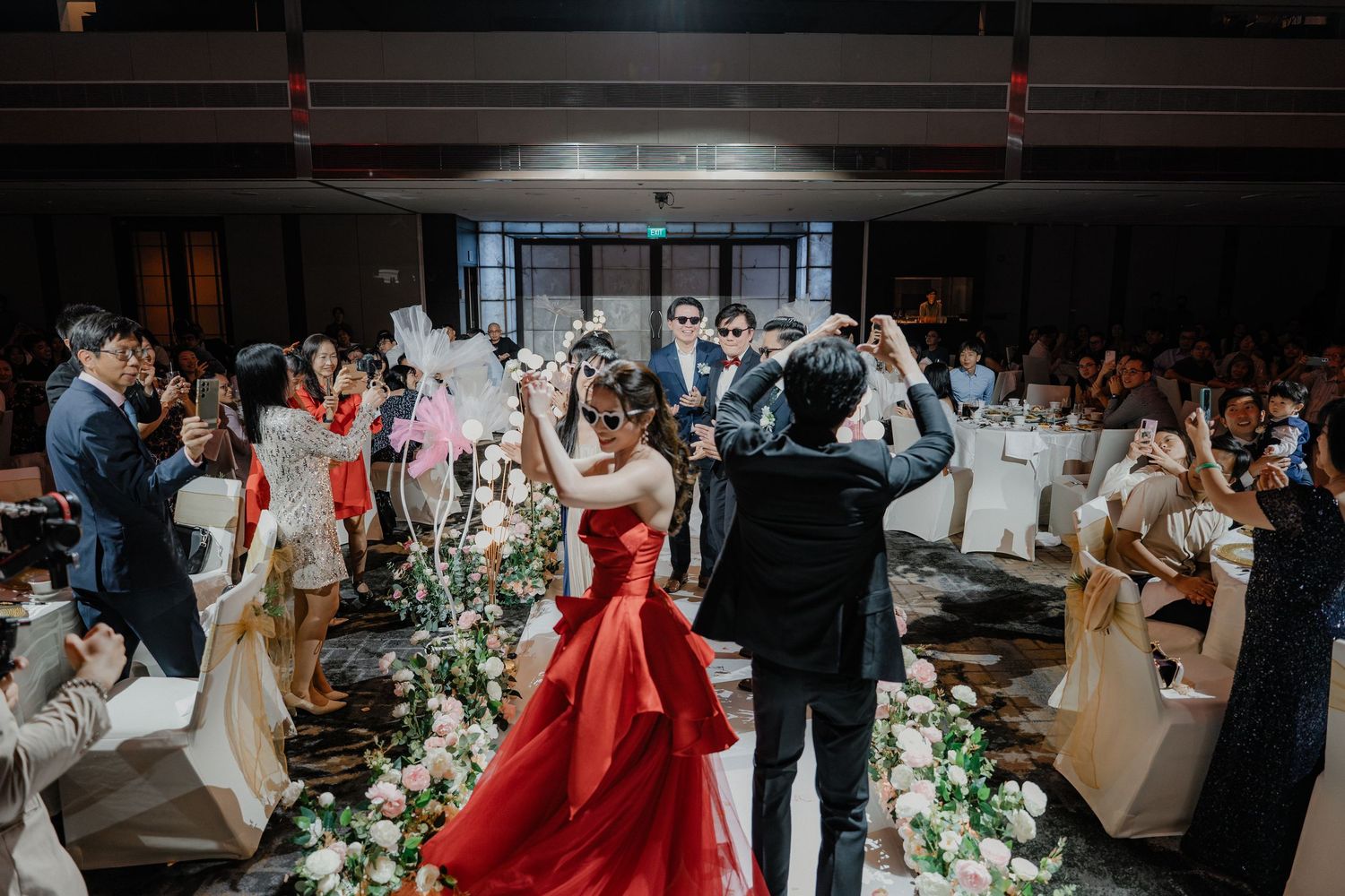 Wedding reception guests enjoying a celebration in an elegant banquet hall with floral decorations and ambient lighting.